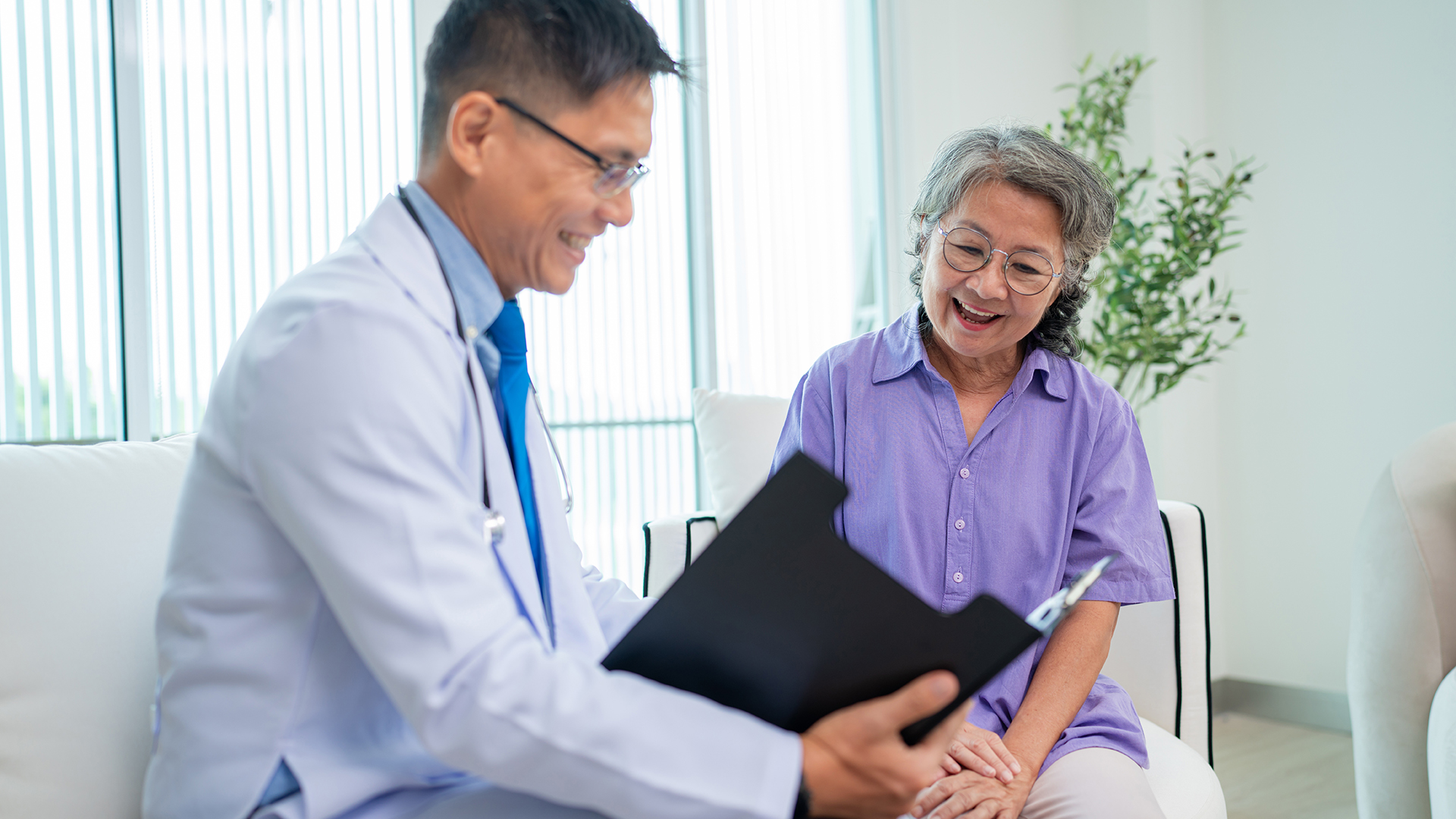 Mature male doctor taking care and talking mature female patient