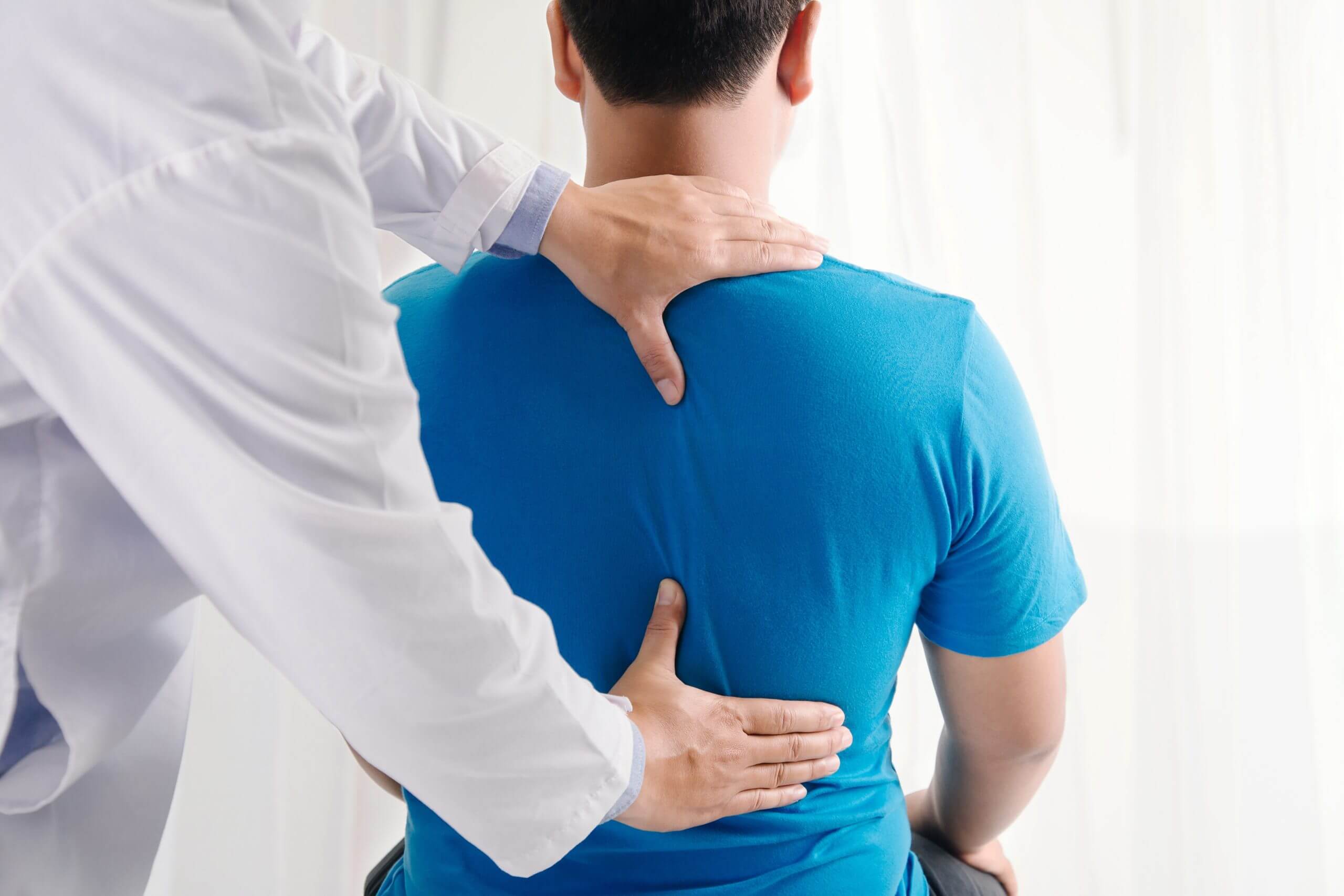 Doctor physiotherapist doing healing treatment on man's back.Bac