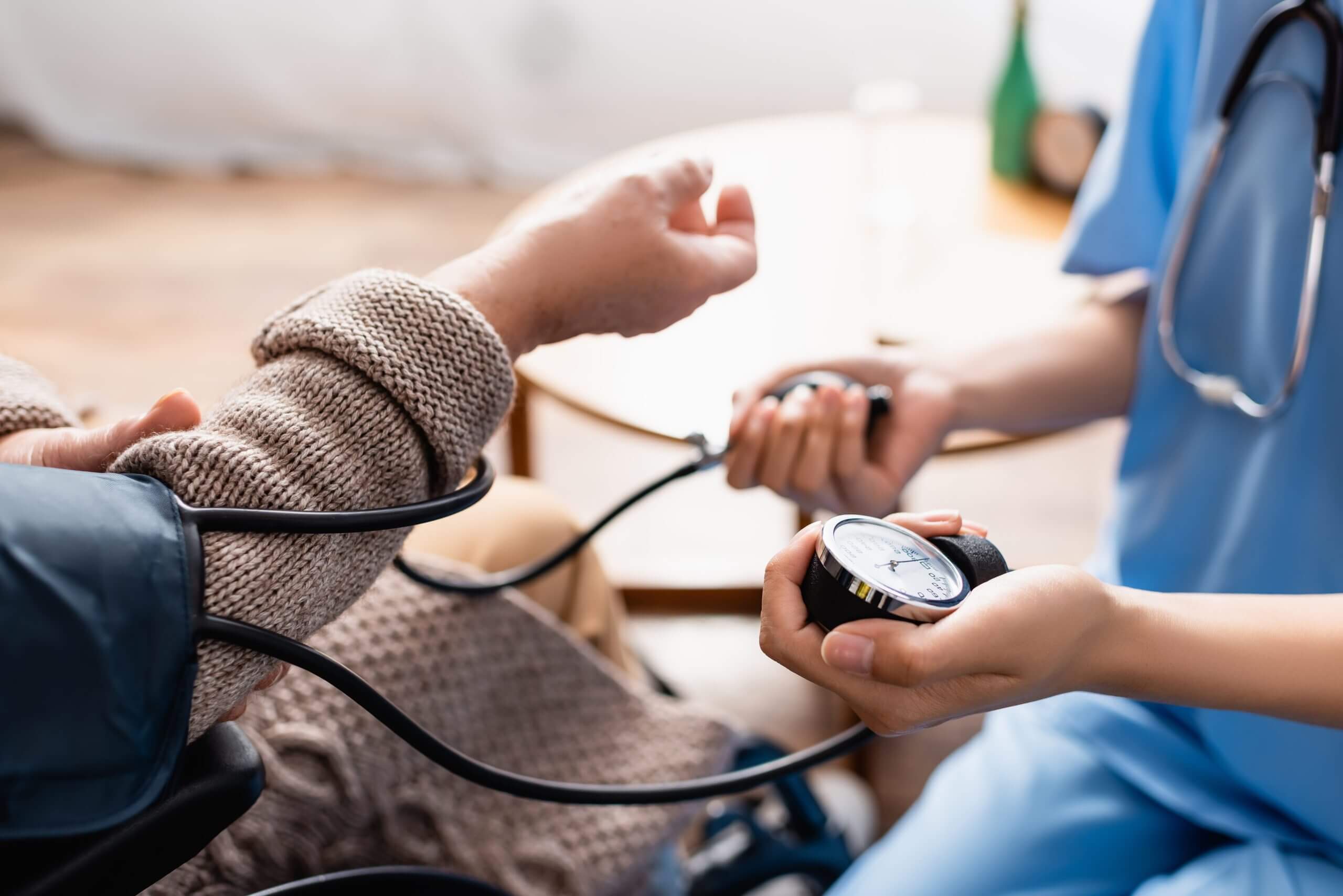 partial view of young nurse measuring blood pressure of senior w